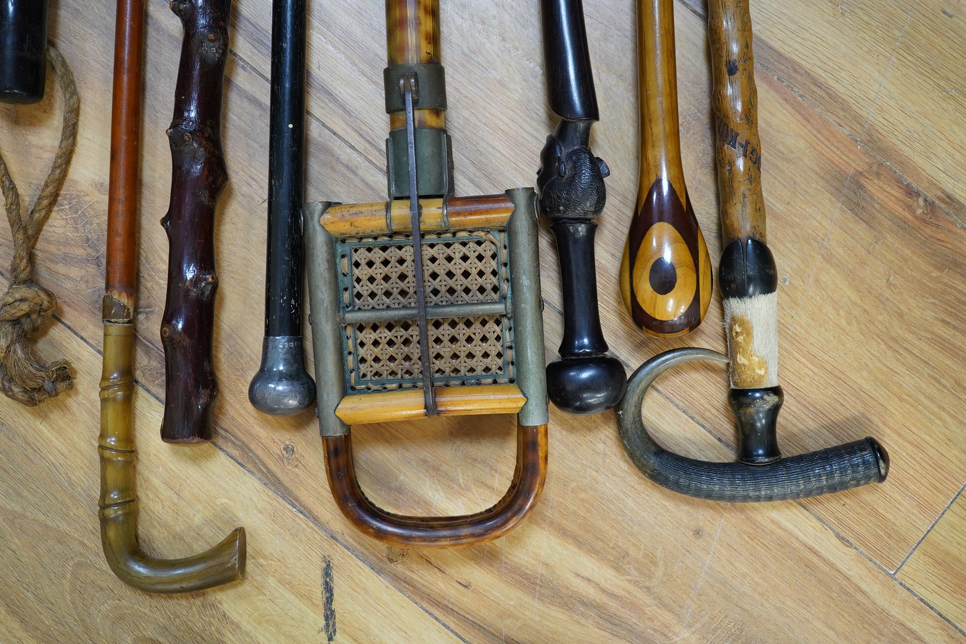 An Edwardian oak stickstand and sundry walking sticks including a bamboo shooting stick, silver topped cane etc. condition varies